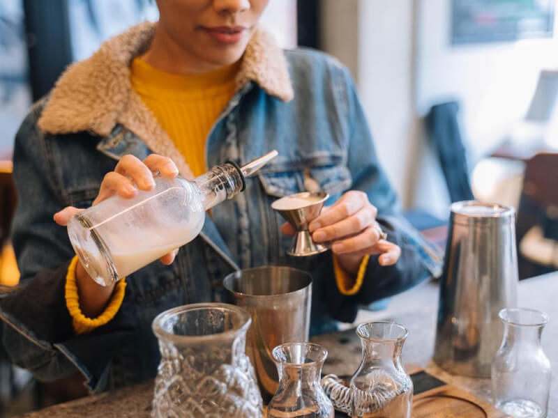 Person in a denim jacket pouring a drink at a cocktail class